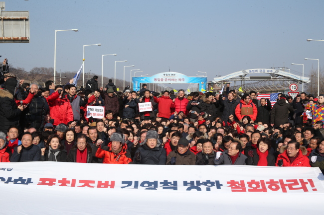 Lawmakers with the main opposition Liberty Korea Party and conservative activists stage a sit-in against a North Korean delegation's visit on Sunday, in front of the Tongil Bridge. (Yonhap)