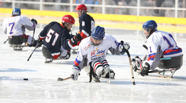 Para ice hockey players compete in an exhibition match at a special ice rink in front of Seoul City Hall in Seoul to promote the PyeongChang Paralympic Winter Games on Monday. (Yonhap)