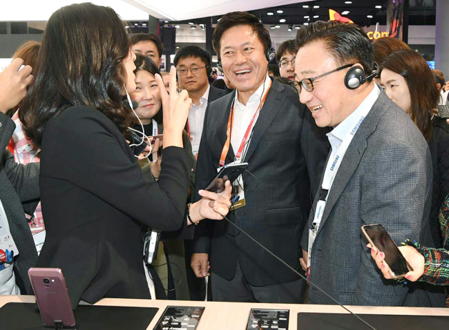 SK Telecom CEO Park Jung-ho (center) and DJ Koh (right), president and Head of IT & Mobile Communications Division, Samsung Electronics, look at Samsung's Galaxy S9 at the tech firm's booth at Mobile World Congress in Barcelona, Spain, Monday. (SK Telecom)