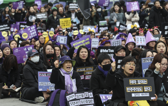 Participants at the 34th Korean Women's Conference march in the streets in downtown Seoul on Sunday shout slogans while holding up signs. The event was held to mark the UN-designated International Women's Day. (Yonhap)