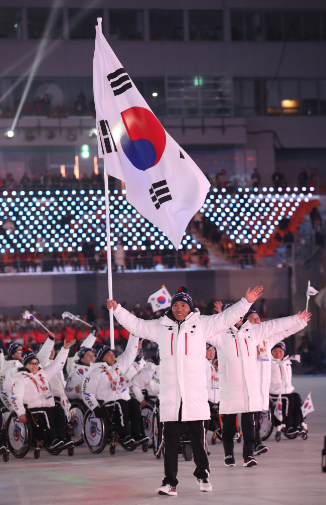 Para Nordic skier Sin Eui-hyun carries the South Korean national flag while the national team enters the Olympic Stadium in Gangwon Province at the opening ceremony for the PyeongChang Paralympics on Friday. (Yonhap)