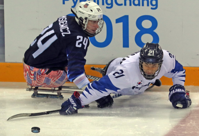 Lee Ju-seung (right) of South Korea tries to win the puck against Joshua Misiewicz of the United States during the men's ice hockey Group B game at the PyeongChang Winter Paralympics at Gangneung Hockey Centre in Gangneung, Gangwon Province on Tuesday. (Yonhap)