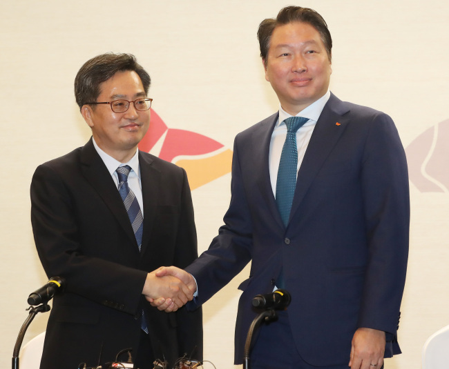 Finance Minister Kim Dong-yeon (L) shakes hands with Chey Tae-won, chairman of SK Group, before a meeting in Seoul on March 14, 2018. (Yonhap)