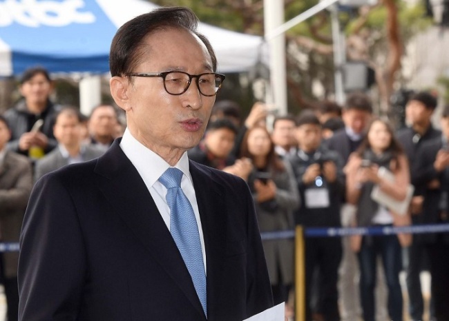 Former President Lee Myung-bak stands in the photo line at the Seoul Central District Prosecutors’ Office early in the morning for questioning Wednesday. (Yonhap)