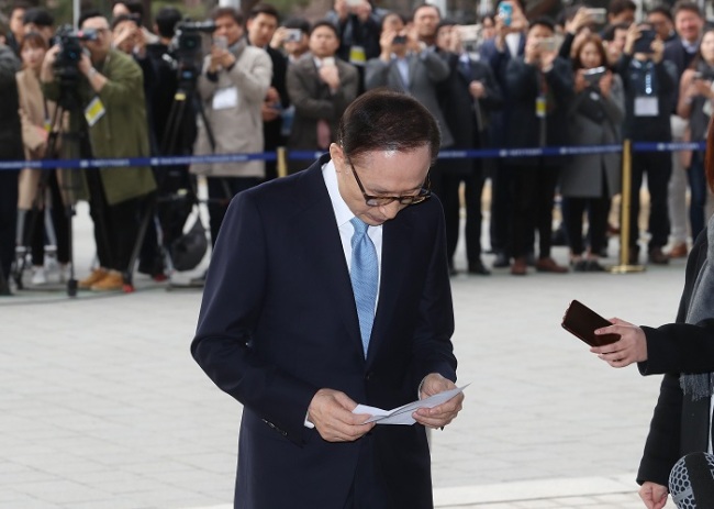Former President Lee Myung-bak stands in the photo line at the Seoul Central District Prosecutors’ Office early in the morning for questioning Wednesday. (Yonhap)