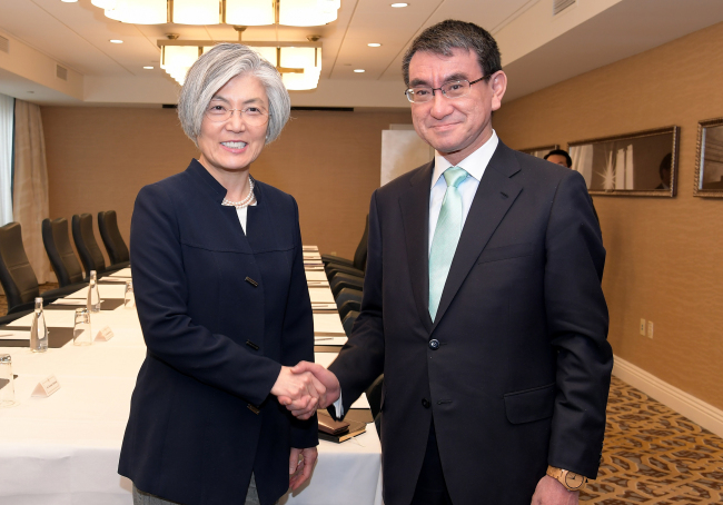South Korean Foreign Minister Kang Kyung-wha (left) and Japanese Foreign Minister Taro Kono shake hands at a meeting in Washington on Saturday. (Ministry of Foreign Affairs-Yonhap)