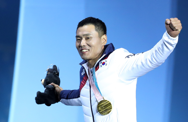 Para Nordic skier Sin Eui-hyun, who won gold in the men's 7.5km sitting cross-country skiing, raises his arms as he exits the podium at the medal ceremony held at Olympic Plaza in PyeongChang, Gangwon Province on Saturday. (Yonhap)