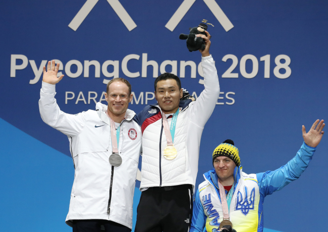 Sin Eui-hyun (center) poses at a medal ceremony held at the Medal Plaza in Gangneung, Gangwon Province, Saturday, after winning the gold medal in the men’s 7.5-km sitting cross-country skiing event. Next to him are silver-medalist Daniel Cnossen (left) of the US and Maksym Yarovyi of Ukraine. (Yonhap)