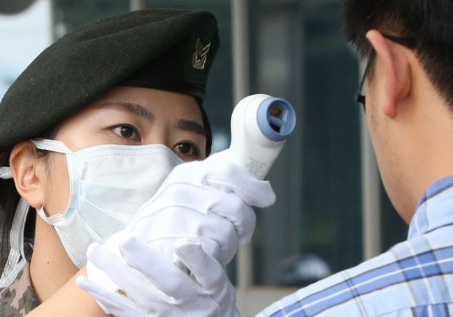 A Korean soldier checks a person for MERS symptoms (Yonhap)