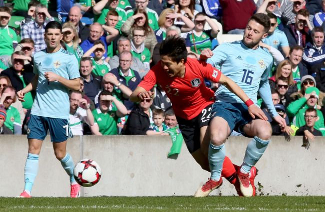 South Korea's midfielder Kwon Chang-hoon (C) is tackled by Northern Ireland's midfielder Oliver Norwood during the international friendly football match between Northern Ireland and South Korea at at Windsor Park in Belfast on March 24, 2018. (AFP-Yonhap)