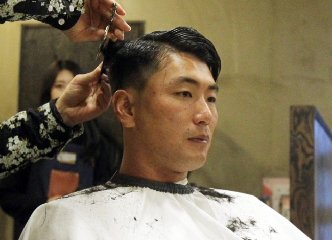 In this photo provided by the SK Wyverns baseball club, Kim Kwang-hyun, the team's starting pitcher, gets a haircut on March 25, 2018, in Incheon, 40 kilometers west of Seoul. Kim will donate his hair to help make wigs for children who've lost their hair following cancer treatment. (Yonhap)