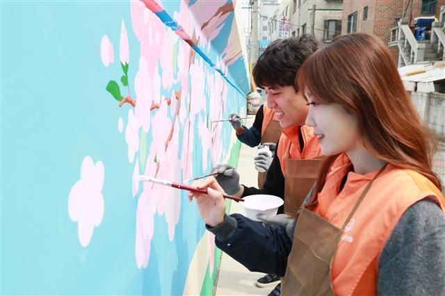 한화갤러리아가 지난 27일 진행한 ‘벚꽃 벽화 그리기’ 사회공헌활동에서 참가자들이 벚꽃 나무와 꽃잎 그림을 그리고 있다.