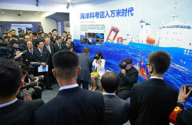 A photograph released by North Korea‘s Rodong Shinmun on Wednesday shows North Korean leader Kim Jong-un and his wife Ri Sol-ju trying on VR goggles at the Chinese Academy of Science in Beijing. (Yonhap)