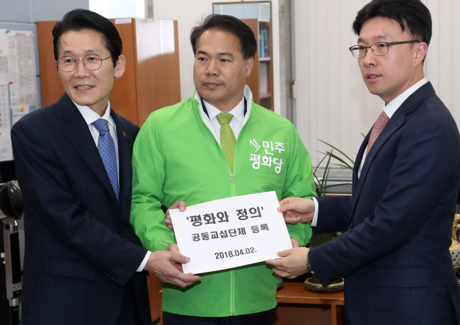 Lee Yong-ju (C), the vice floor leader of the Party for Democracy and Peace, and Youn So-ha (L), the vice floor leader of the Justice Party, submit a form to register their parties' new floor negotiation bloc at the National Assembly in Seoul on April 2. (Yonhap)