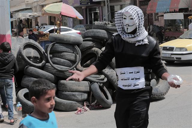 <YONHAP PHOTO-2265> A Palestinian youth wearing a Guy Fawkes mask collects money to support the protest, in Khan Younis, in the southern Gaza Strip, on April 4, 2018. A tent protest continues in support of Palestinian refugees returning to lands they fled or were expelled from during the 1948 war surrounding Israel's creation. Photo by Ismael Mohamad/UPI/2018-04-05 09:00:55/ <저작권자 ⓒ 1980-2018 ㈜연합뉴스. 무단 전재 재배포 금지.>