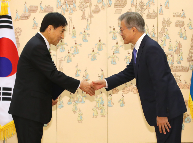 President Moon Jae-in (R) hands a certificate of appointment to Bank of Korea Gov. Lee Ju-yeol in a ceremony held at his office Cheong Wa Dae in Seoul on April 9, 2018, appointing the incumbent head of the central bank to a second four-year term. (Yonhap)
