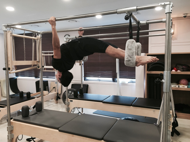 Sports creator Leo Jung performs an advanced stretch on the Pilates Cadillac. (Photo courtesy of Leo Jung)