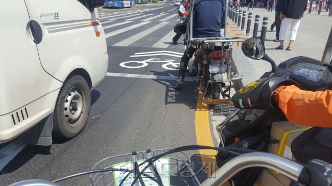 서울 종로 자전거전용차로 위에 차량이 불법주차돼 있다(왼쪽 사진). 또 자전거와 일반 차량이 뒤엉키거나(가운데) 승객 승하차를 위해 택시가 멈춰 서기도 한다.  이원율 기자/yul@heraldcorp.com
