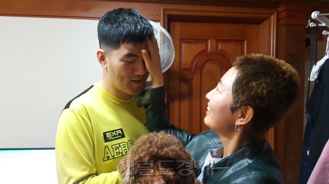 외출 전 발달장애인 현우 씨의 운동화 끈을 묶어주고 있는 어머니 김경미 씨.  그는 발달장애인이 지역사회에서 어울릴 수 있는 기반이 하루빨리 마련됐으면 좋겠다고 말한다.