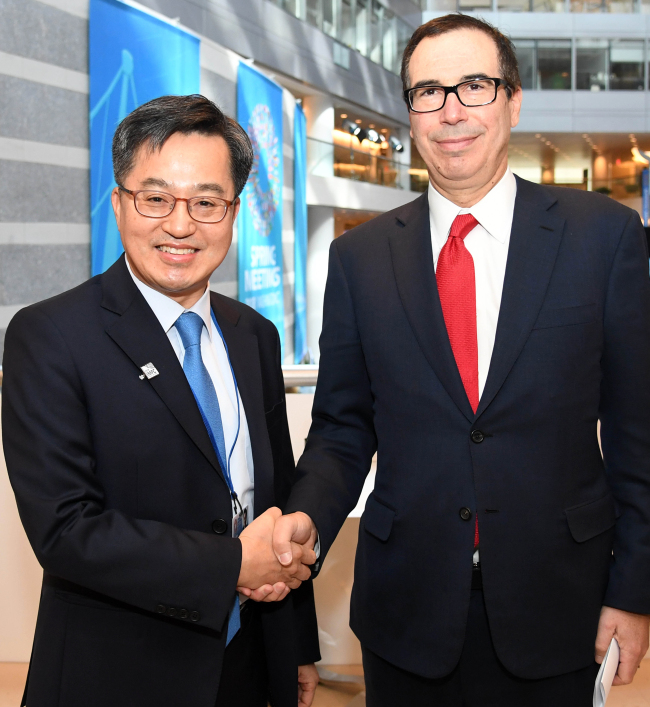 South Korean Finance Minister Kim Dong-yeon (L) shakes hands with US Treasury Secretary Steven Mnuchin before a meeting in Washington, on April 21, 2018. (Yonhap)
