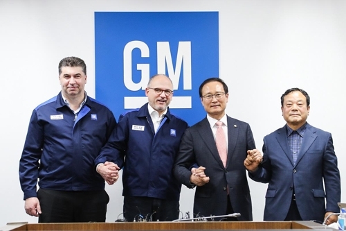 GM Korea President and Chief Executive Kaher Kazem, GM Executive Vice President Barry Engle, ruling Democratic Party lawmaker Hong Young-pyo and Moon Seung, who represents GM Korea's 140,000 subcontractors, hold hands after the company and its union reached a tentative restructuring agreement at the main Bupyeong plant, just west of Seoul on April 23. (Yonhap)