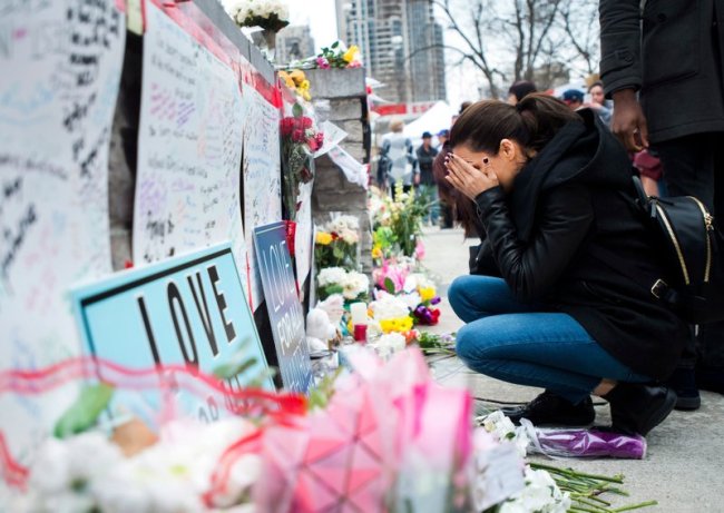 A woman fights back tears at a memorial along Yonge Street, Tuesday, April 24, in Toronto, the day after a driver drove a van down sidewalks, striking and killing numerous pedestrians in his path. (AP)