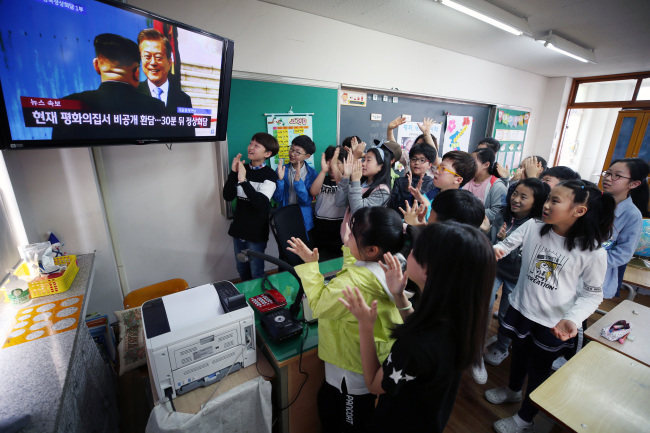 Students at an elementary school in Gwangju, Jeolla Province, cheer in joy as they watch North Korean leader Kim Jong-un shake hands wiht his South Korean counterpart Moon Jae-in in the first summit for the two Koreas in over a decade. (Yonhap)