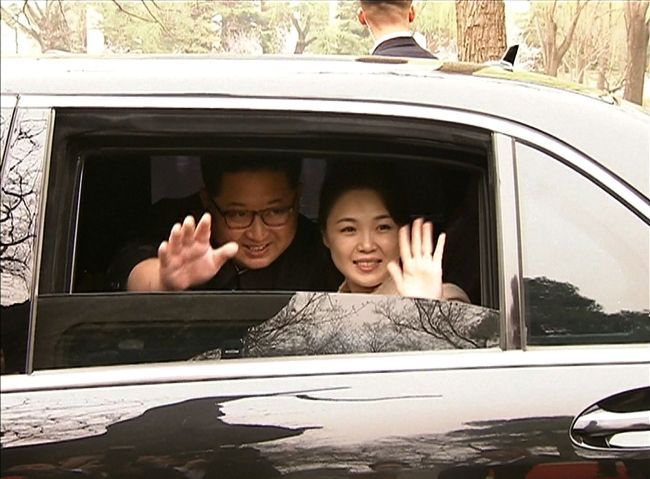 North Korean leader Kim Jong-un and his wife Ri Sol-ju wave from a car as they bid farewell to Chinese counterpart Xi Jinping and his wife Peng Liyuan in Beijing on March 27. (AP-Yonhap)