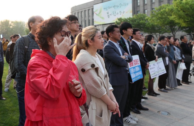 Seoul citizens tear up as they watch the leaders of two Koreas announce the Panmunjeom Declaration on Friday in central Seoul. (Yonhap)