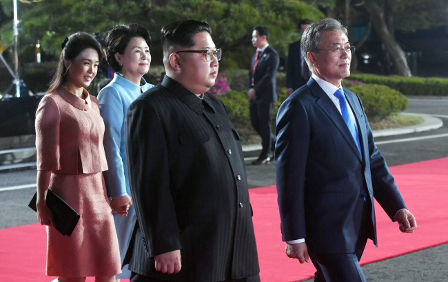 North Korean first lady Ri Sol-ju (far left) and her South Korean counterpart Kim Jung-sook (second from right) hold hands as they leave the Peace House after a banquet event on Friday, along with the North Korean leader Kim Jong-un (second from right) and the South Korean President Moon Jae-in (far right).