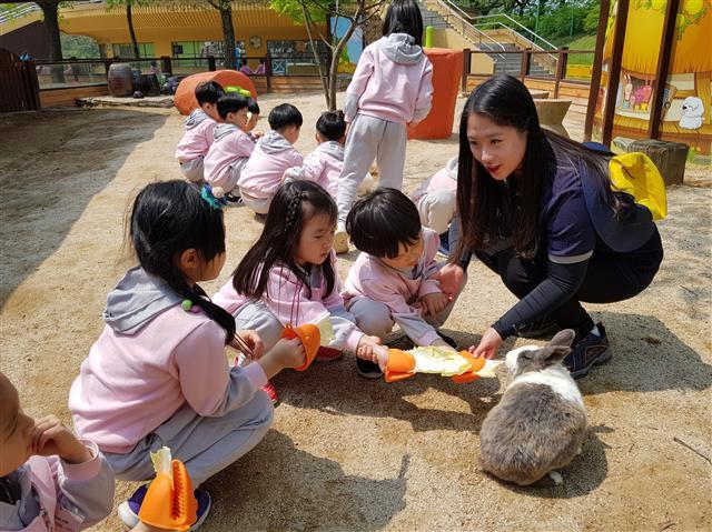 서울 뉴딜일자리 ‘쥬 아카데미 동행전문가’로 일하는 강승구 씨가 미어캣에게 먹이를 주고 있다(왼쪽 사진). 서울 뉴딜일자리 ‘쥬 아카데미 동행전문가’로 일하는 안은혜 씨가 어린이들 상대로 토끼에게 먹이 주는 법을 알려주고 있다.  [제공=서울동물원]