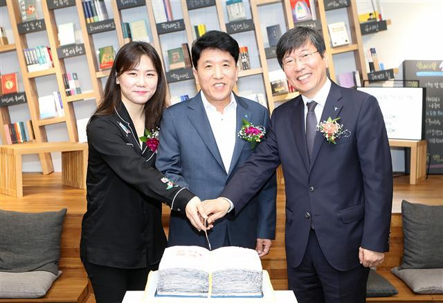 2일 오전 KEB하나은행은 서울 광화문역 지점에서 ‘컬처뱅크 2호점’ 개점식을 진행, ‘힐링 서점’ 개념의 점포를 선보였다. 함영주 KEB하나은행장(가운데)과 김진양 북바이북 대표(왼쪽), 하응호 광화문역 지점장이 책 모양으로 된 축하 케이크를 자르고 있다. [제공=KEB하나은행]