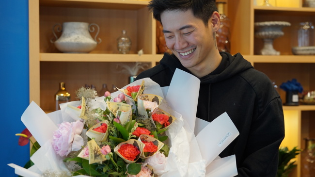 Florist Jung Jun-ho poses for a picture with a money-wrapped flower bouquet at Peony Pepe flower shop, located in Cheongdam-dong, southern Seoul on May 1. (Park Ju-young/The Korea Herald)　