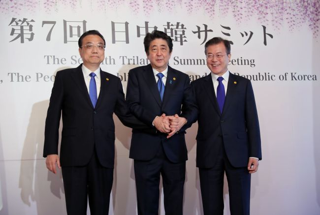 South Korea's President Moon Jae-in (R), China's Premier Li Keqiang (L) and Japan's Prime Minister Shinzo Abe (C) join hands as they pose for photos prior to the start of their trilateral summit in Tokyo on May 9, 2018.(AFP-Yonhap)
