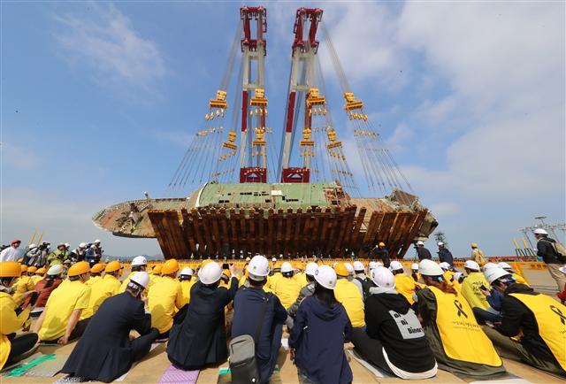 <YONHAP PHOTO-2712> 세월호 40도가량 바로 섰다 (목포=연합뉴스) 박철홍 기자 = 10일 오전 전남 목포시 목포신항에서 좌현을 바닥에 댄 채 거치 된 세월호가 40도가량 세워지는 모습을 유가족이 지켜보고 있다. 2018.5.10 pch80@yna.co.kr/2018-05-10 09:53:50/ <저작권자 ⓒ 1980-2018 ㈜연합뉴스. 무단 전재 재배포 금지.>