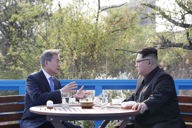 South Korean President Moon Jae-in (left) and North Korean leader Kim Jong-un talk on a bridge in Panmunjeom on April 27. (Yonhap)