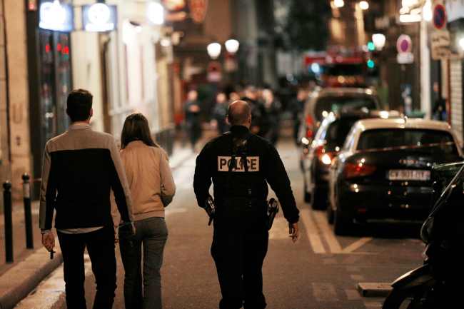 A policeman walks next to a couple in a street of Paris centre after one person was killed and several injured by a man armed with a knife, who was shot dead by police in Paris on May 12, 2018. (AFP-Yonhap)