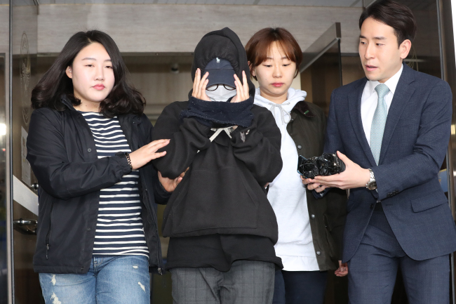 A female model (second from left) is being questioned by reporters after being questioned by police for leaking a nude photograph of her male colleague at a police station in Seoul on Saturday. She was eventually brought into custody. (Yonhap)
