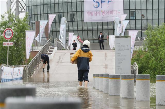 <YONHAP PHOTO-1534> 길이 끊겨도 배달은 한다 (서울=연합뉴스) 김도훈 기자 = 18일 오전 밤사이 내린 비로 잠긴 반포한강공원에서 한 택배기사가 플로팅 아일랜드로 물품을 배달하고 있다. 2018.5.18 photo@yna.co.kr/2018-05-18 10:02:52/ <저작권자 ⓒ 1980-2018 ㈜연합뉴스. 무단 전재 재배포 금지.>