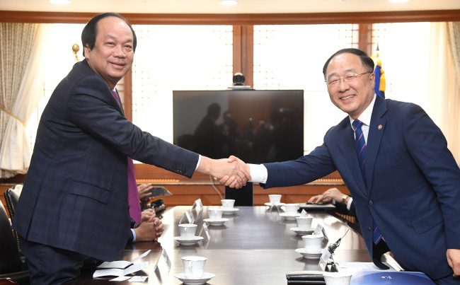 Government Policy Coordination Minister Hong Nam-ki (R) shakes hands with Mai Tien Dung, minister and chairman of Vietnam's Government Office, during a meeting in Seoul on May 23, 2018. (Yonhap)