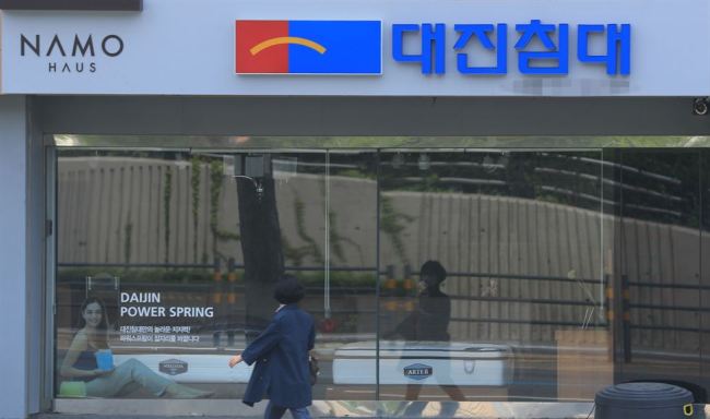 A citizen walks past a Daijin Bed store in Seoul. (Yonhap)