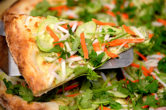 Slice's banh mi pizza pairs cheese and lemongrass-infused pork sausage with a piquant, cliantro-based sauce, cucumber, pickled carrots and daikon radish. Park Hyun-koo/The Korea Herald