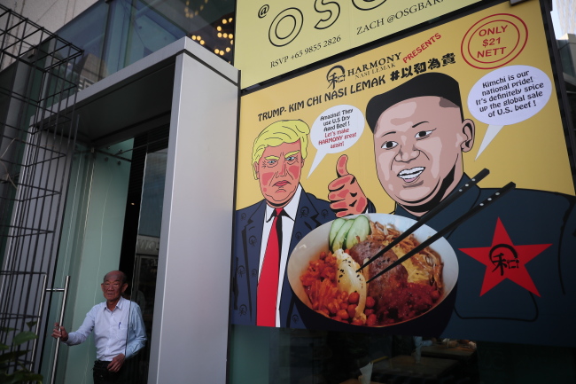 Pictured is a poster depicting US President Donald Trump (center), North Korean leader Kim Jong-un (right), and a promotional dish of 'Trump-Kim Chi Nasi Lemak' at a restaurant in Singapore on June 6, 2018. (EPA-Yonhap)