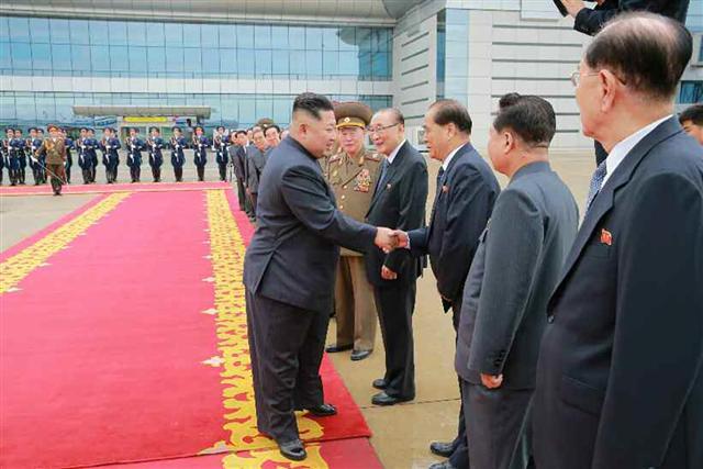북한 노동신문은 11일 김정은 북한 국무위원장이 전날 첫 북미정상회담을 위해 싱가포르를 방문했다고 보도하며 김 위원장이 평양을 출발하는 모습을 담은 사진들을 공개했다. 사진은 김 위원장이 공항에 배웅나온 당·정·군 고위간부들과 작별인사를 나누는 모습. (왼쪽) 도널드 트럼프 미국 대통령이 김정은 국무위원장과의 회담을 위해 10일 싱가포르 파야 레바르 공군기지에 도착, 영접나온 비비안 발라크리쉬난 싱가포르 외무장관과 악수를 나누고 있다.   [평양·싱가포르=노동신문·AFP연합뉴스]