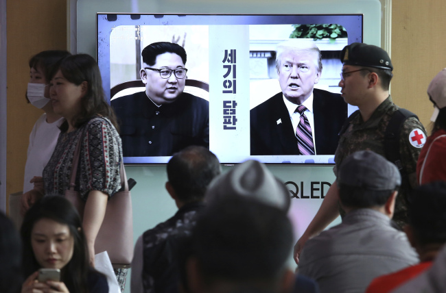 Viewers look on at a TV screen showing file footage of US President Donald Trump (right) and North Korean leader Kim Jong Un during a news program at Seoul Railway Station in Seoul on Monday. (AP-Yonhap)