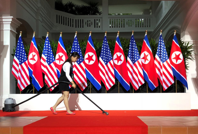 A worker vacuums the stage at the spot where U.S. President Donald Trump and North Korea's leader Kim Jong Un are expected to meet and shake hands for the first time at the start of their summit at the Capella Hotel (Reuters)