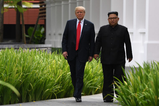 North Korea's leader Kim Jong Un (R) walks with US President Donald Trump (L) during a break in talks at their historic US-North Korea summit, at the Capella Hotel on Sentosa island in Singapore on June 12, 2018. Donald Trump and Kim Jong Un became on June 12 the first sitting US and North Korean leaders to meet, shake hands and negotiate to end a decades-old nuclear stand-off. / AFP PHOTO