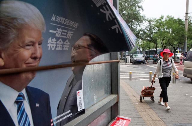 A Chinese woman pulls a trolley bag past a Chinese magazine cover showing US President Donald Trump and North Korean leader Kim Jong Un at a newsstand in Beijing, China on Wednesday. (AP)