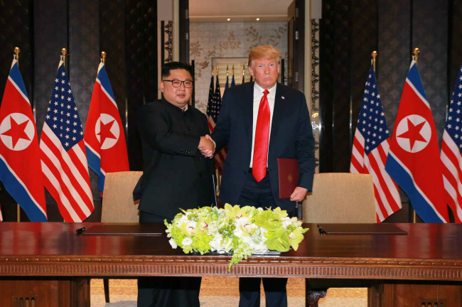 This photo, carried by North Korea's state-run newspaper, Rodong Sinmun, shows North Korea's leader Kim Jong-un (left) shaking hands with US President Donald Trump after signing an agreement at their summit in Singapore, Tuesday. (For Use Only in the Republic of Korea. No Redistribution) (Yonhap)