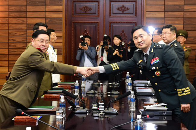 　South Korean Maj. Gen. Kim Do-gyun (facing camera) and a North Korean delegate shake hands as a South Korean delegation for high-level inter-Korean military talks crosses over to the North’s side of Panmunjeom in the Demilitarized Zone on Thursday. (Yonhap)